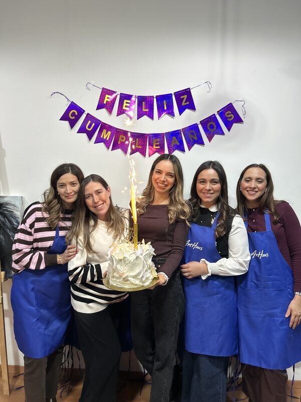 Personas celebrando cumpleaños en Arthaus sosteniendo un pastel con delantales azules